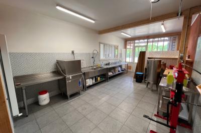 Salle de bain avec plafond en bois, carrelage coloré, douche avec rideau et lavabo sur meuble blanc.