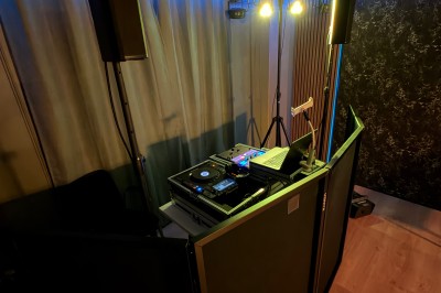 Poste de DJ avec platines, table de mixage et ordinateur portable dans une ambiance lumineuse violette et verte.