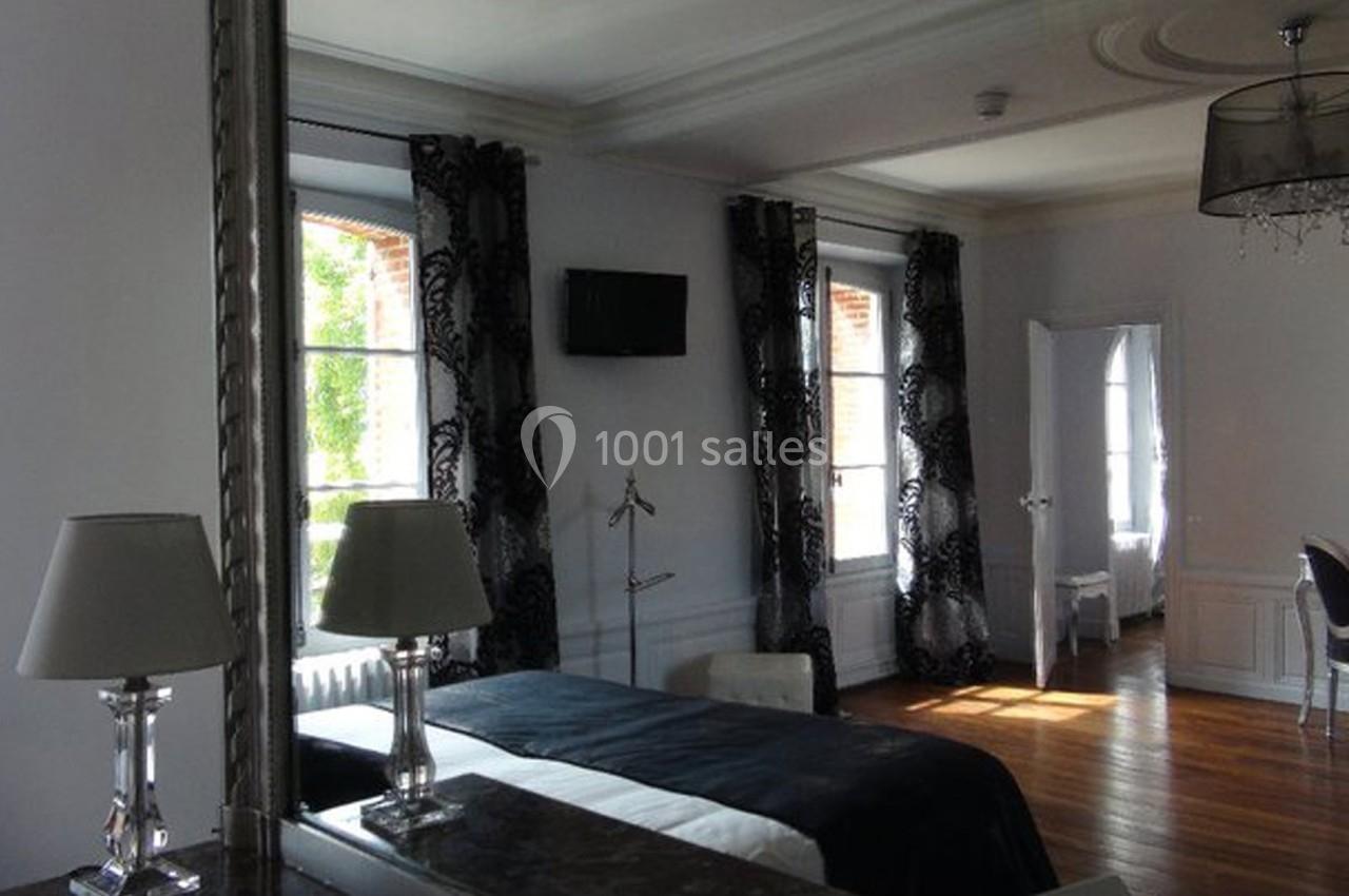 Chambre lumineuse avec lit double, rideaux noirs, bureau avec miroir et parquet en bois clair.
