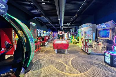 Avion suspendu dans un espace intérieur spacieux avec des écrans, des sièges et une décoration industrielle.