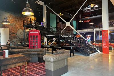 Avion suspendu dans un espace intérieur spacieux avec des écrans, des sièges et une décoration industrielle.