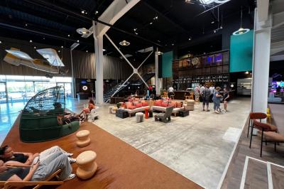 Avion suspendu dans un espace intérieur spacieux avec des écrans, des sièges et une décoration industrielle.