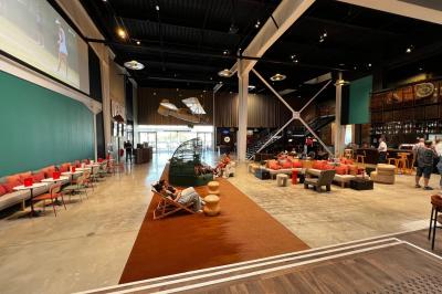 Avion suspendu dans un espace intérieur spacieux avec des écrans, des sièges et une décoration industrielle.