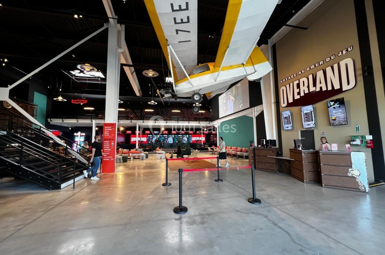 Avion suspendu dans un espace intérieur spacieux avec des écrans, des sièges et une décoration industrielle.