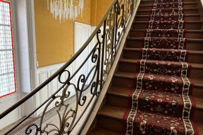 Chambre lumineuse avec lit double, draps blancs, coussins gris, bureau en bois et parquet en bois clair.