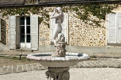 Chambre lumineuse avec lit double, draps blancs, coussins gris, bureau en bois et parquet en bois clair.