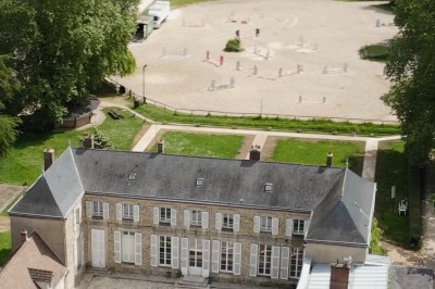 Chambre lumineuse avec lit double, draps blancs, coussins gris, bureau en bois et parquet en bois clair.