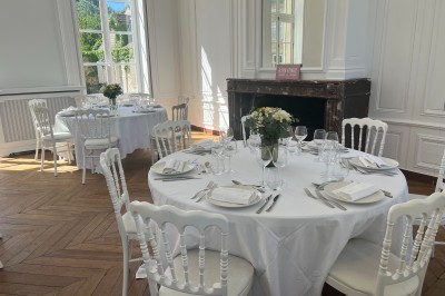 Chambre lumineuse avec lit double, draps blancs, coussins gris, bureau en bois et parquet en bois clair.