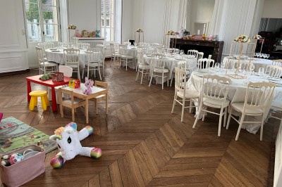 Chambre lumineuse avec lit double, draps blancs, coussins gris, bureau en bois et parquet en bois clair.