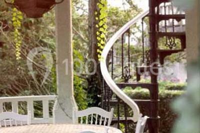 Lit double avec draps blancs, plaid bleu et tables de chevet avec lampes dans une chambre à la décoration rustique.