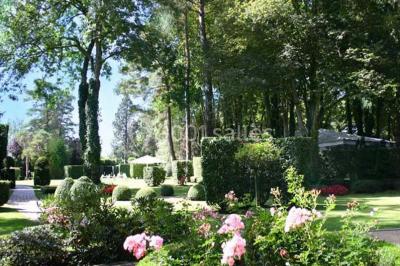 Lit double avec draps blancs, plaid bleu et tables de chevet avec lampes dans une chambre à la décoration rustique.