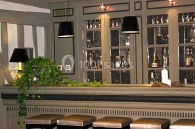 Lit double avec draps blancs, plaid bleu et tables de chevet avec lampes dans une chambre à la décoration rustique.