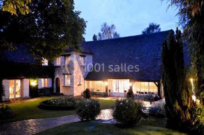 Lit double avec draps blancs, plaid bleu et tables de chevet avec lampes dans une chambre à la décoration rustique.