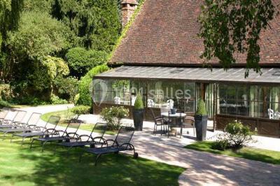 Lit double avec draps blancs, plaid bleu et tables de chevet avec lampes dans une chambre à la décoration rustique.