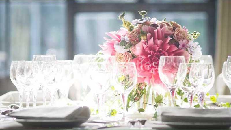 Centre de table floral rose entouré de verres à pied disposés sur une table dressée.