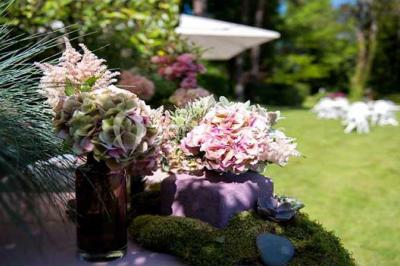 Lit double avec draps blancs, plaid bleu et tables de chevet avec lampes dans une chambre à la décoration rustique.