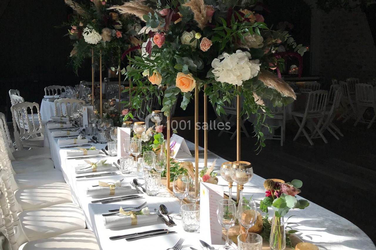 Table de réception élégamment décorée avec des fleurs colorées sur des supports dorés et une vaisselle raffinée.