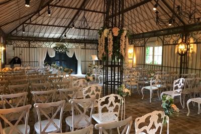 Lit double avec draps blancs, plaid bleu et tables de chevet avec lampes dans une chambre à la décoration rustique.
