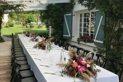 Lit double avec draps blancs, plaid bleu et tables de chevet avec lampes dans une chambre à la décoration rustique.