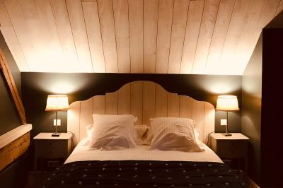 Lit double avec draps blancs, plaid bleu et tables de chevet avec lampes dans une chambre à la décoration rustique.