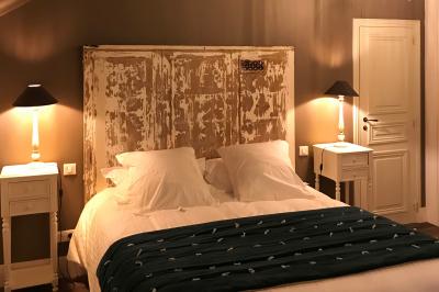 Lit double avec draps blancs, plaid bleu et tables de chevet avec lampes dans une chambre à la décoration rustique.