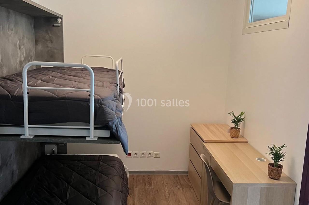 Chambre avec lits superposés, bureau en bois clair, deux petites plantes et fenêtre apportant de la lumière naturelle.