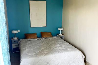 Vue d'un grand salon lumineux avec carrelage beige, cuisine ouverte et baies vitrées donnant sur un jardin.