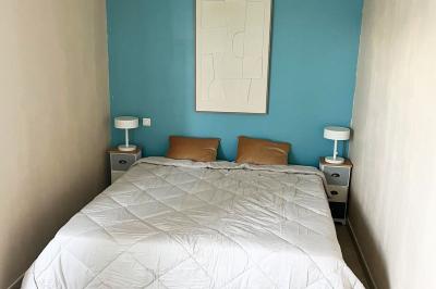 Vue d'un grand salon lumineux avec carrelage beige, cuisine ouverte et baies vitrées donnant sur un jardin.