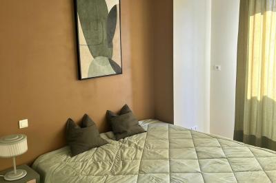 Vue d'un grand salon lumineux avec carrelage beige, cuisine ouverte et baies vitrées donnant sur un jardin.