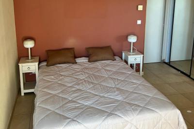 Vue d'un grand salon lumineux avec carrelage beige, cuisine ouverte et baies vitrées donnant sur un jardin.