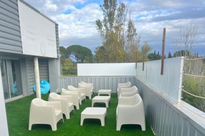 Vue d'un grand salon lumineux avec carrelage beige, cuisine ouverte et baies vitrées donnant sur un jardin.