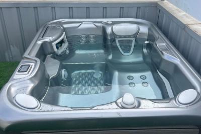 Vue d'un grand salon lumineux avec carrelage beige, cuisine ouverte et baies vitrées donnant sur un jardin.