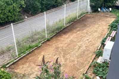 Vue d'un grand salon lumineux avec carrelage beige, cuisine ouverte et baies vitrées donnant sur un jardin.