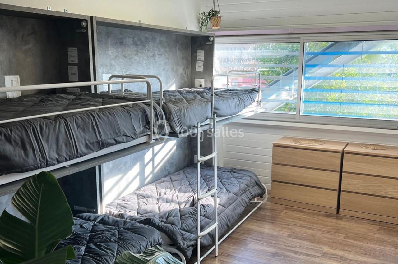 Lit superposé moderne avec draps gris dans une chambre lumineuse, parquet au sol et grande fenêtre avec vue extérieure.