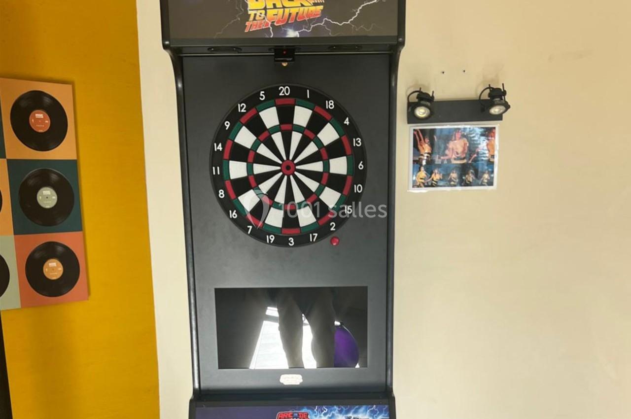 Jeu de fléchettes électronique avec écran intégré, décoré d'éléments rétro et d'une affiche de film.