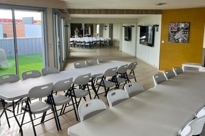 Grande pièce lumineuse avec carrelage beige, cuisine ouverte, baies vitrées donnant sur un jardin avec pelouse.