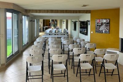 Grande pièce lumineuse avec carrelage beige, cuisine ouverte, baies vitrées donnant sur un jardin avec pelouse.