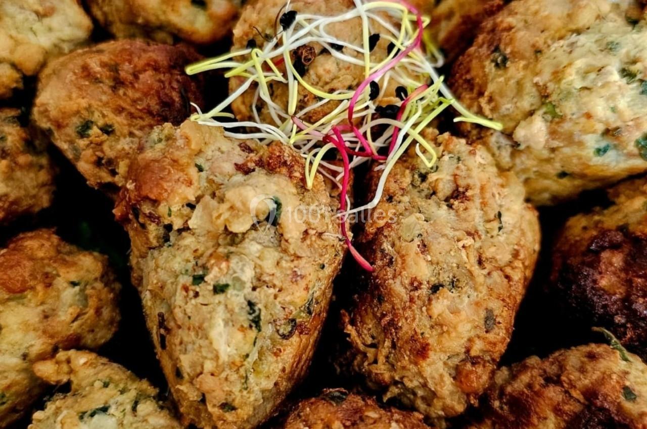 Boulettes végétariennes dorées garnies de jeunes pousses et accompagnées de tomates cerises rouges.
