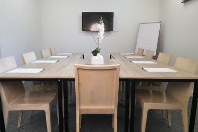 Salle de réunion avec des chaises disposées en cercle, une table basse au centre et un écran mural.