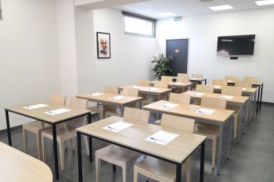 Salle de réunion avec des chaises disposées en cercle, une table basse au centre et un écran mural.