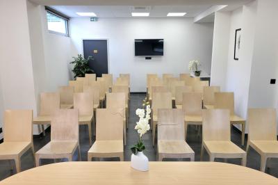 Salle de réunion avec des chaises disposées en cercle, une table basse au centre et un écran mural.