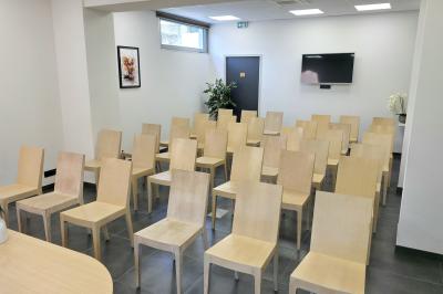 Salle de réunion avec des chaises disposées en cercle, une table basse au centre et un écran mural.