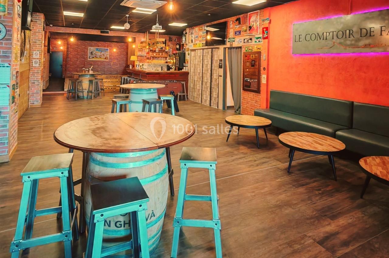 Salle de bar avec tables en bois, tabourets métalliques, mur rouge avec enseigne lumineuse et décorations vintage.