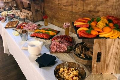 Table garnie de verrines, brochettes de fruits frais et plateaux de donuts colorés sur une nappe décorative.