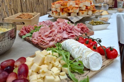 Table garnie de verrines, brochettes de fruits frais et plateaux de donuts colorés sur une nappe décorative.