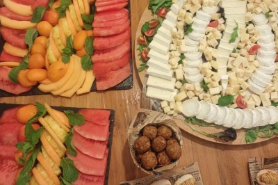 Table garnie de verrines, brochettes de fruits frais et plateaux de donuts colorés sur une nappe décorative.