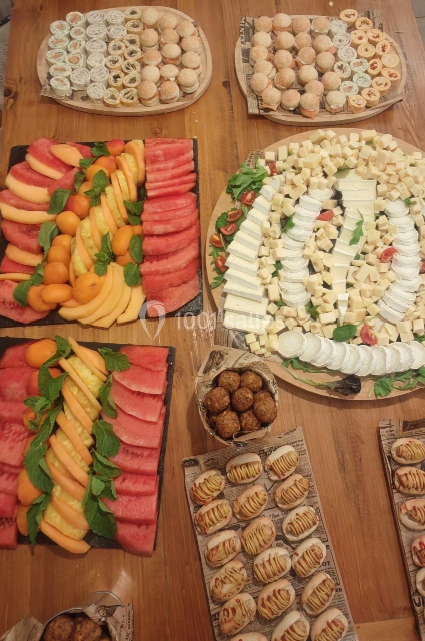 Plateaux variés de fruits, fromages, sushis et pâtisseries disposés sur une table en bois.