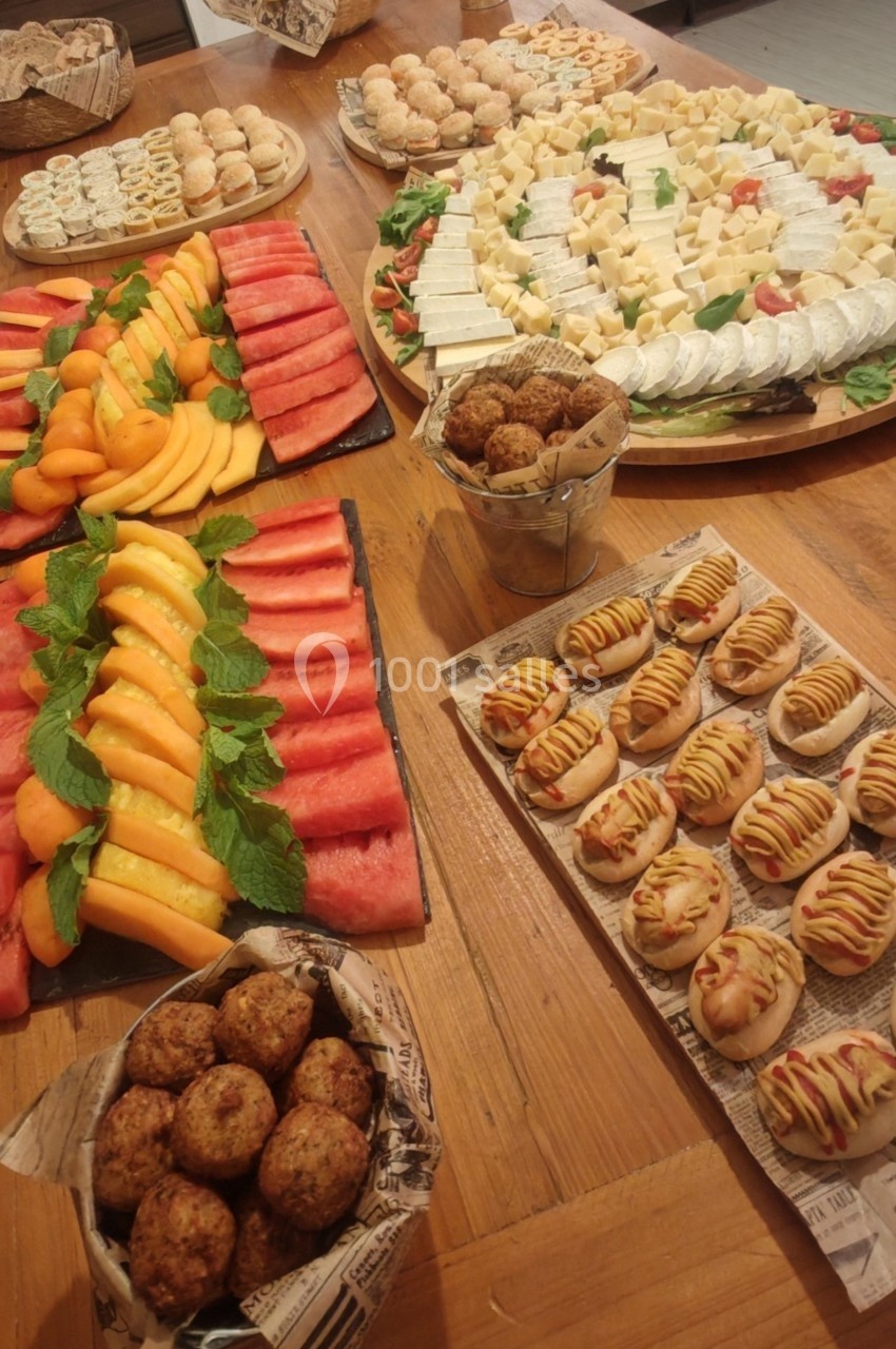 Plateau de fruits frais, fromages, pains garnis et boulettes disposés sur une table en bois.