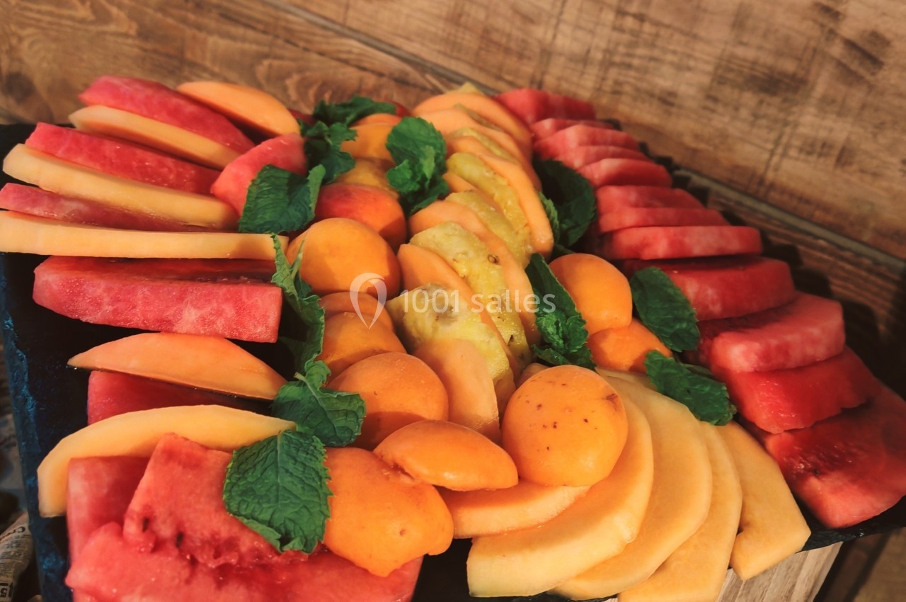 Plateau de fruits variés avec pastèques, melons, abricots et feuilles de menthe, disposés sur un fond en bois.