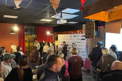 Des personnes discutent dans un espace intérieur avec des murs en briques, un écran affichant une cheminée et une ambiance…